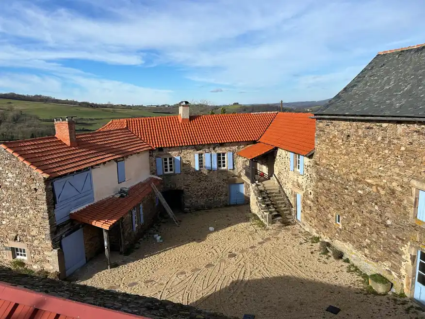 Bâtiment ancien en pierre et sa toiture neuve vus depuis la cour