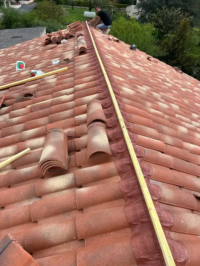 Pose des tuiles faîtières sur un pan terminé